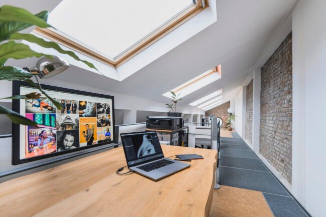 Moderner Arbeitsplatz mit Laptop und großem Monitor, der eine visuelle Webdesign-Referenz in einer Kölner Agenturumgebung zeigt.